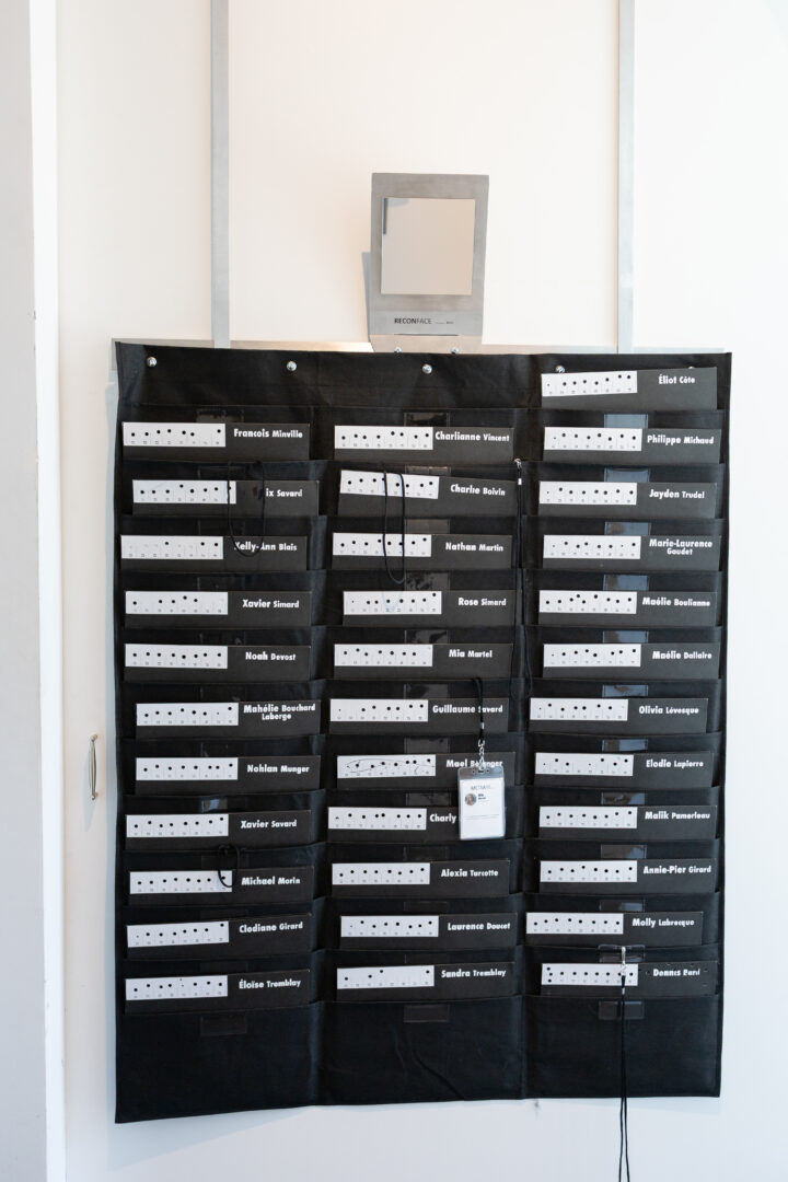 Photographie de l'appareil de reconaisance faciale et le porte document des collaborateurs (élèves) de l'exposition-témoin METAARS de Dennis Baril faisant suite à la résidence Art actuel en milieu scolaire à l'école secondaire des Batisseurs - Édifice Jonquière.